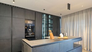 A modern kitchen with a large island, dark cabinetry, and a glass-fronted storage unit. - Villa Suva Punta Elite with Private Pool (Vir)