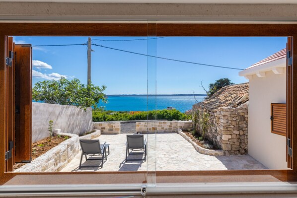 A view from a balcony with a stone wall, two chairs, and a clear blue sky. - Holiday Home Fortica with Sea View (Ražanac)
