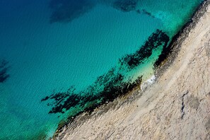 An aerial view of a beach with clear turquoise waters and a rocky shoreline. - Holiday Home Fortica with Sea View (Ražanac)