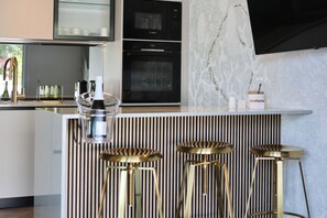 Eine moderne Küche mit einem Bosch-Ofen, einer Bar mit Hockern und einer Wandverkleidung.