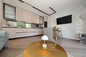 Eine moderne Küche mit weißen Schränken, einem großen Fenster und einem an der Wand befestigten Flachbildfernseher.