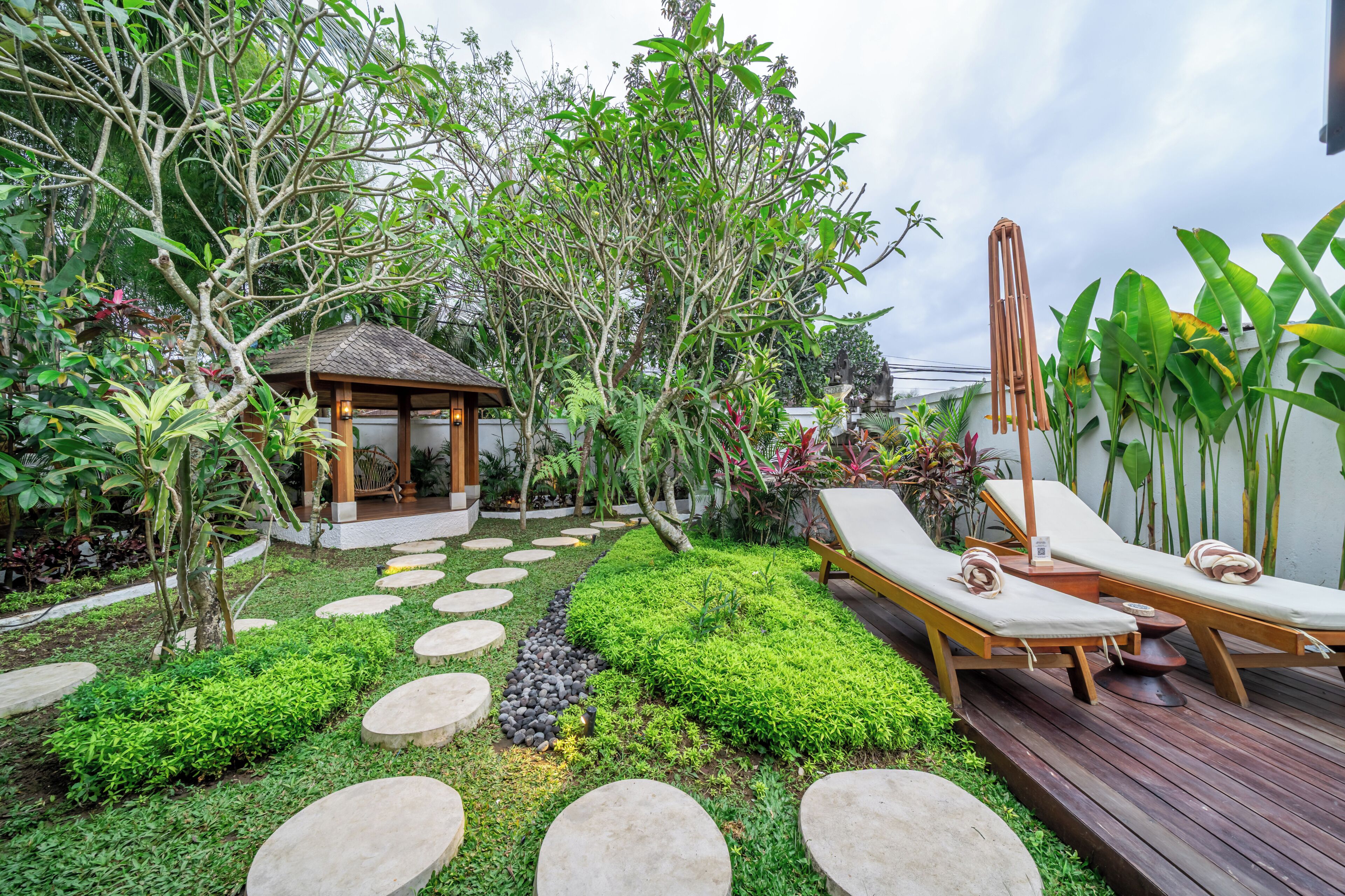 A garden with a gazebo, lounge chairs, and a wooden deck.