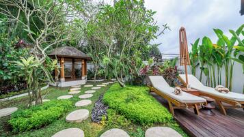 A garden with a gazebo, lounge chairs, and a wooden deck.