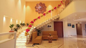Een hotel lobby met een trap versierd met ballonnen, een bank en een muur met een rond patroon.