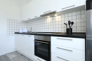 Eine moderne Küche mit weißen Schränken, einer schwarzen Arbeitsplatte und einem Edelstahlbackofen.