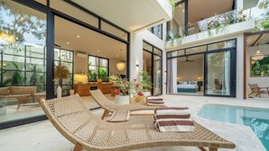 Un interior moderno con piscina, sillas de descanso y una zona de cocina.