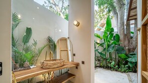 Un baño con tocador de madera, espejo y lavamanos.