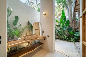 A bathroom with a wooden vanity, a mirror, and a sink. - Feeels Villas 2 (Badung)
