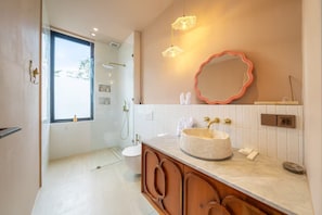 A modern bathroom with a glass shower enclosure, a vanity with a round sink, and a large mirror with a wavy frame. - Feeels Villas 2 (Badung)