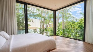 Un dormitorio con una cama grande, vistas a zonas verdes y un diseño moderno.