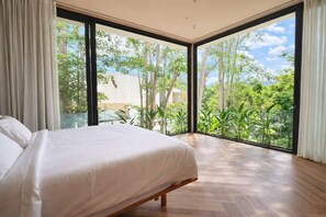 A bedroom with a large bed, a view of greenery, and a modern design. - Feeels Villas 2 (Badung)