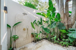A garden with a white wall, a water feature, and various plants. - Feeels Villas 2 (Badung)