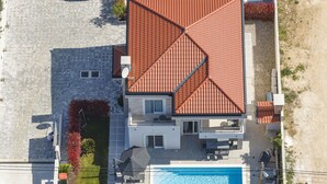 Una casa de dos pisos con piscina, antena parabólica y mobiliario de exterior.