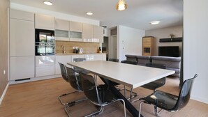 Una cocina moderna con comedor, que incluye una mesa grande y sillas, y un horno empotrado.
