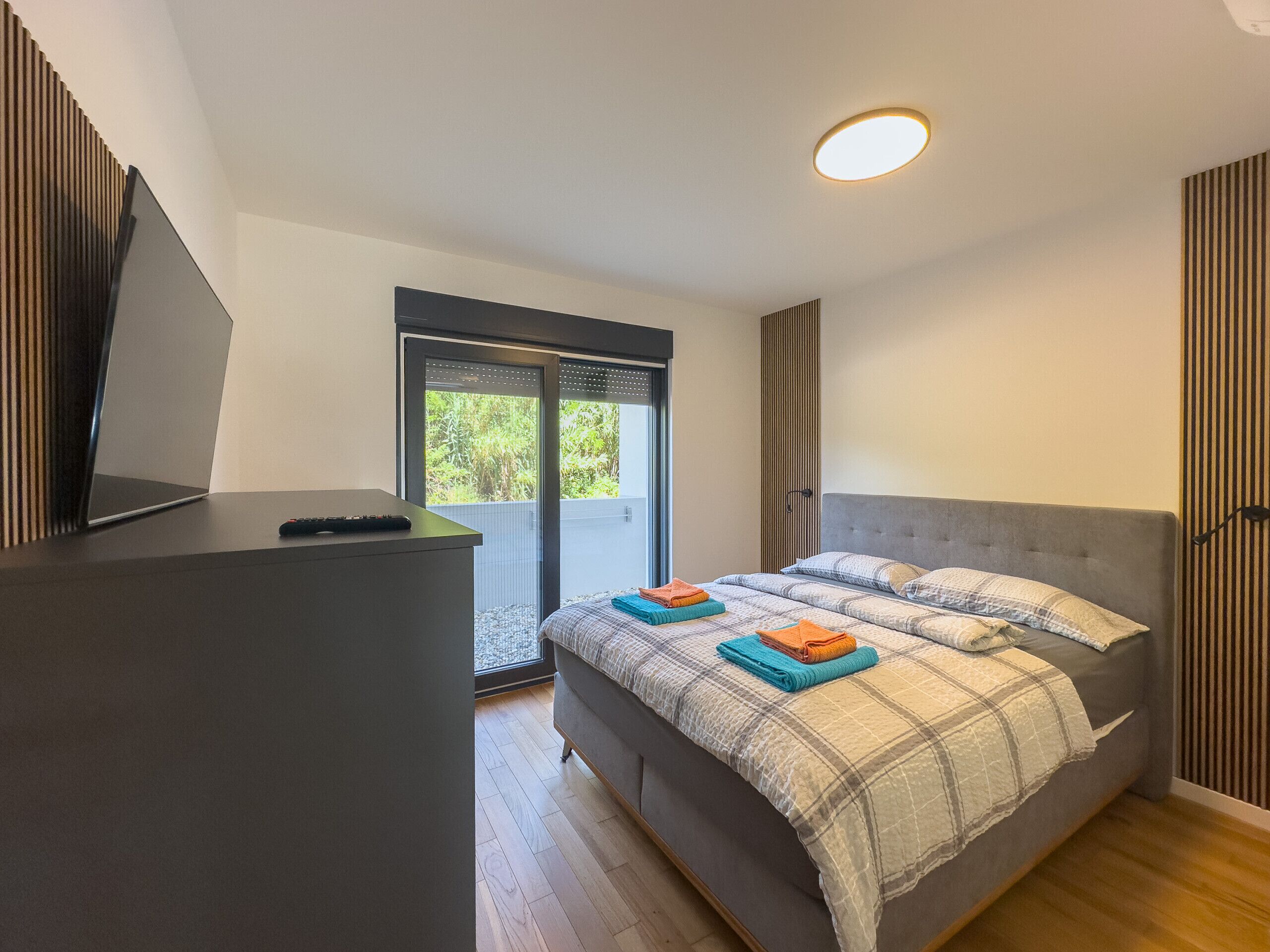 A bedroom with a bed, a desk, and a window.