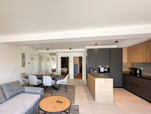 A modern living room with a sofa, a round coffee table, and a dining area with chairs and a table. - Apartment Hugo near the Sea (Privlaka)