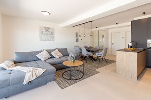 A modern living room with a sofa, coffee table, and dining area. - Apartment Hugo near the Sea (Privlaka)