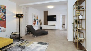 Ett modernt vardagsrum med en soffa, en platt-TV, en bokhylla och konstverk på väggarna.