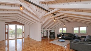 Een ruime loft met hoge plafonds, grote ramen en een houten vloer.