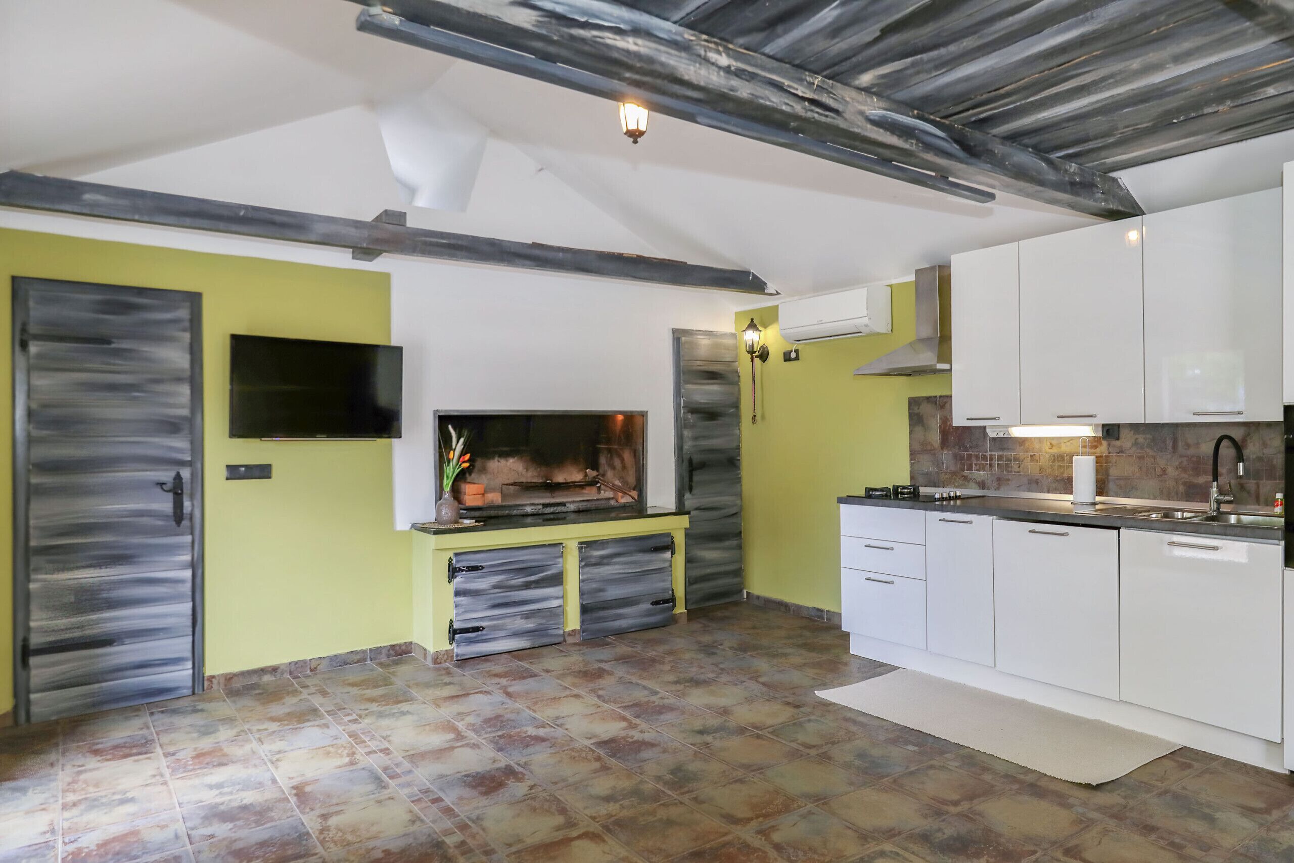 A modern kitchen with white cabinets, a built-in stove, and a large window.