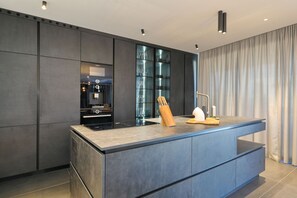 A modern kitchen with a large island, dark cabinetry, and a glass-fronted storage unit. - Villa Suva Punta Luxe with Private Pool (Vir)
