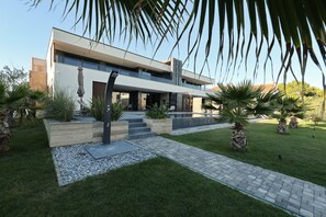 A modern two-story house with a flat roof, large windows, and a paved driveway. - Villa Suva Punta Luxe with Private Pool (Vir)