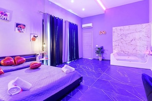 Una habitación de hotel moderna con una cama, una bañera y una amplia pared de mármol.