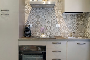 Una cocina con baldosas estampadas, cafetera y horno empotrado.