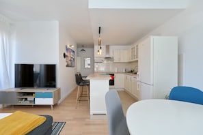 A modern apartment with a TV, dining area, kitchen, and a small island. - Apartment Bajana in Central Location (Zadar)