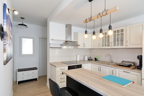 A modern kitchen with white cabinets, a wooden countertop, and pendant lighting. - Apartment Bajana in Central Location (Zadar)