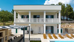 Un bâtiment à deux étages doté d’une piscine, d’un espace extérieur aménagé et d’un patio couvert.