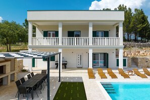 Ein zweistöckiges Gebäude mit Pool, Außenbereich und überdachter Terrasse.