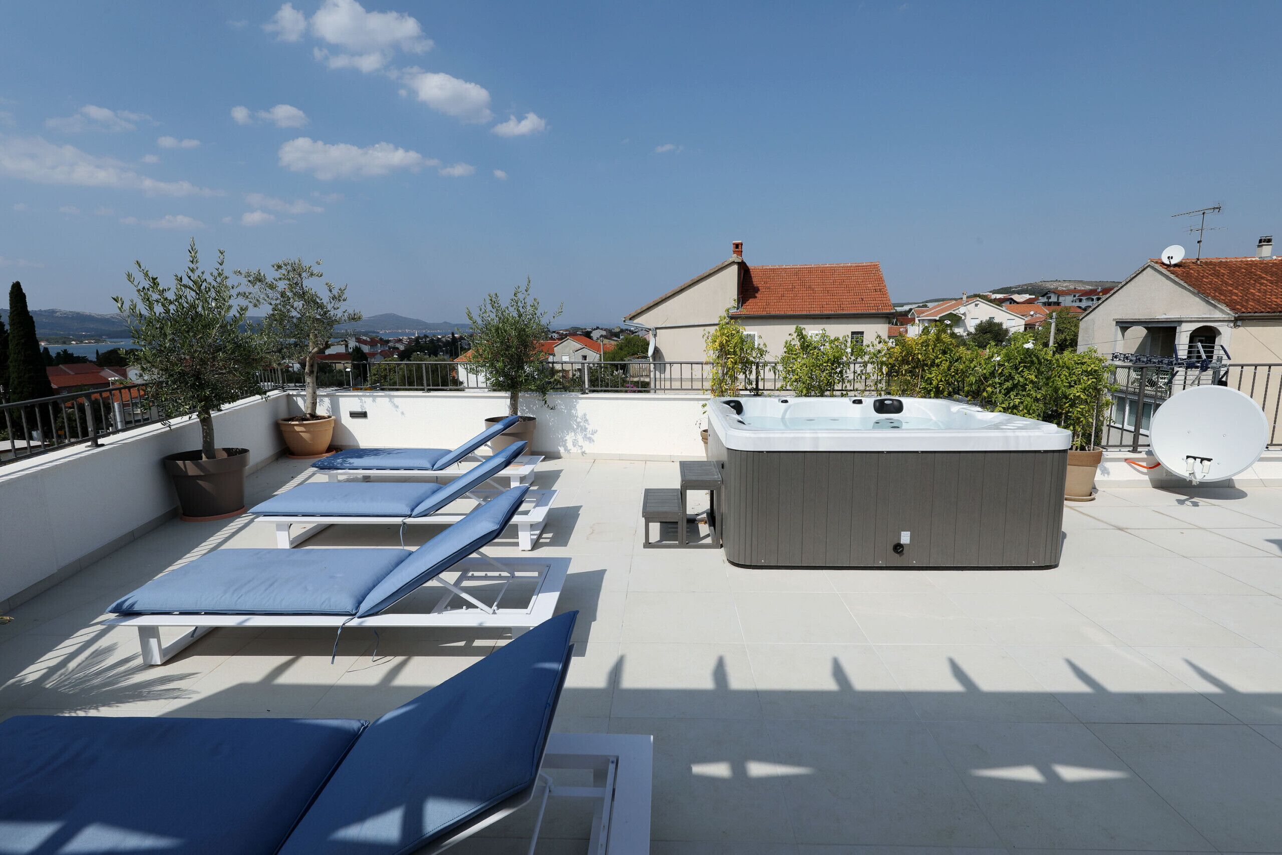 Una terraza en la azotea con sillones de descanso, un jacuzzi y plantas en macetas.