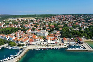 Eine Küstenstadt mit einem Yachthafen, roten Dächern und freiem Blick auf das Meer.