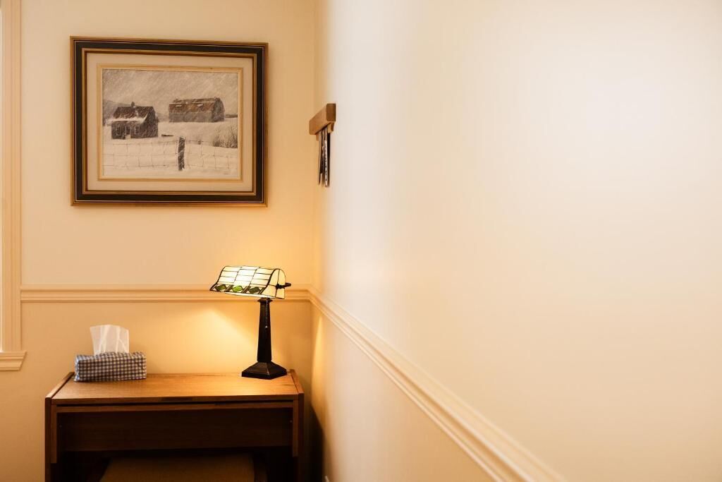 Une photo encadrée représentant un paysage enneigé, une table avec une lampe et une boîte de mouchoirs.