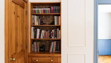 Una estantería de madera con libros, un cajón pequeño y un fondo de pared de ladrillo.