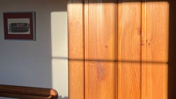 A wooden door with a brass doorknob, a wooden handrail, and a framed picture on the wall.