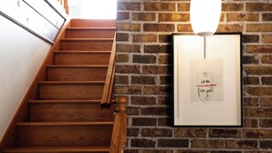 Una escalera de madera con un muro de ladrillo y una obra de arte enmarcada.