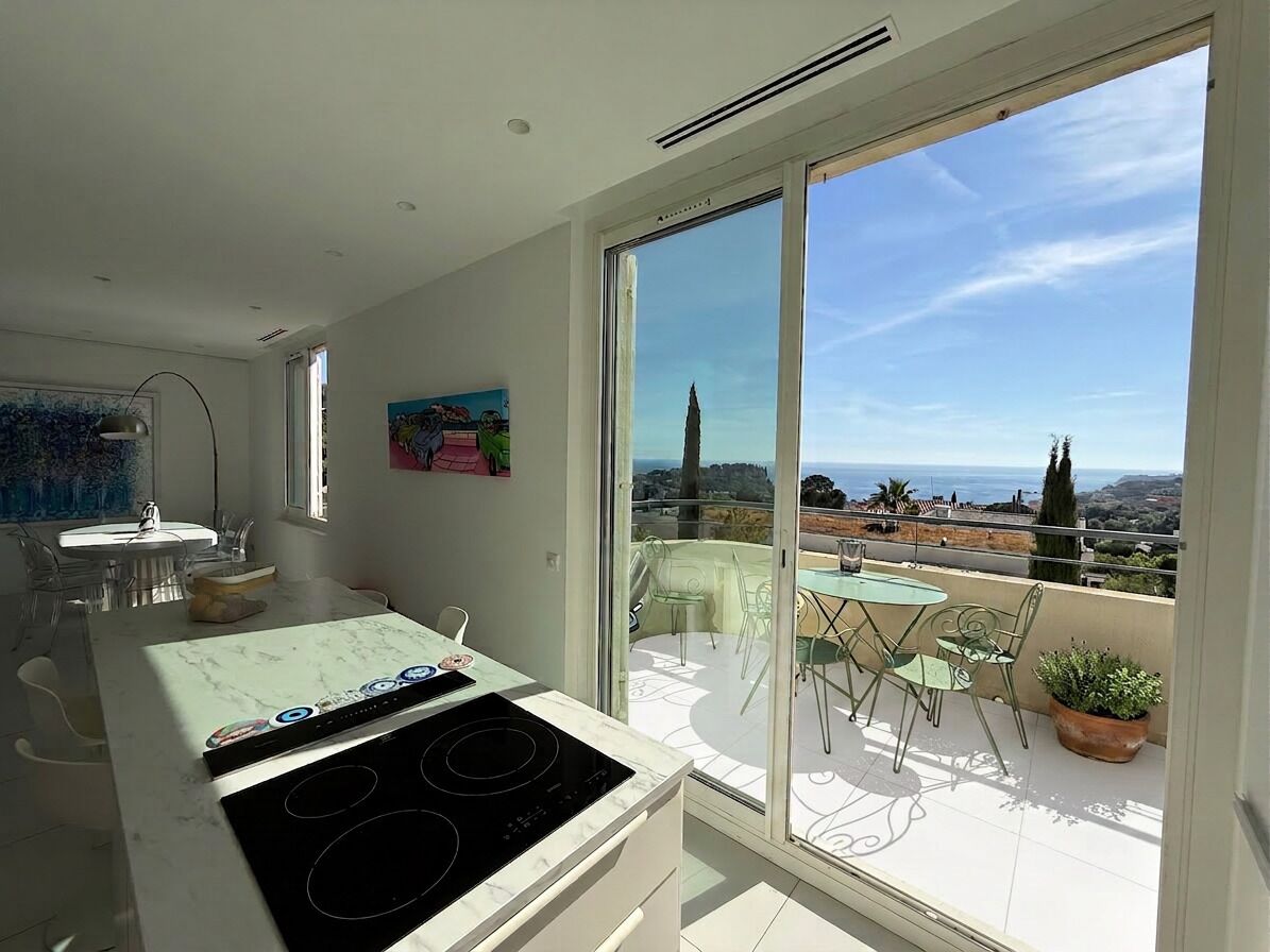 A modern kitchen with a large window, a dining area with chairs, and a view of the cityscape.