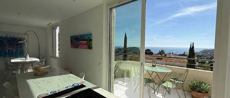 A modern kitchen with a large window, a dining area with chairs, and a view of the cityscape.