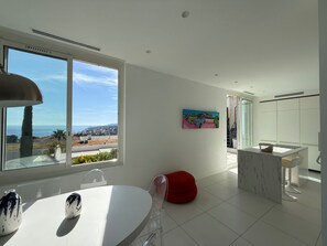 A modern kitchen with a large window, a dining area, and a view of the sea. - Maison Soleil sea view Cassis (Cassis)