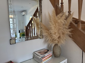 A mirror with floral design, a vase with pampas grass, and a stack of magazines on a white surface. - Maison Soleil sea view Cassis (Cassis)