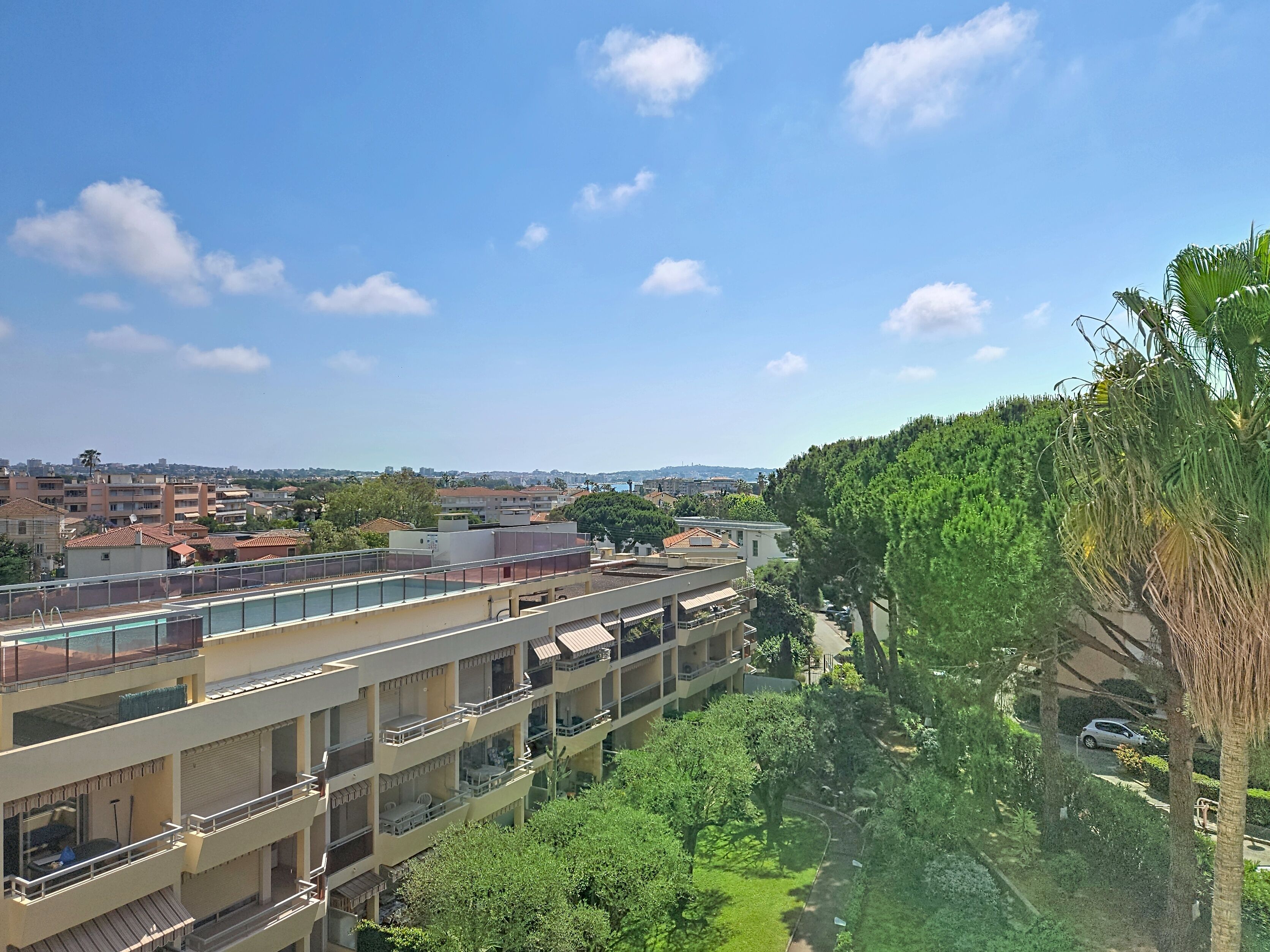 A multi-story building with balconies, a swimming pool, and a view of a residential area.