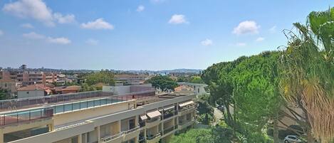 A multi-story building with balconies, a swimming pool, and a view of a residential area.