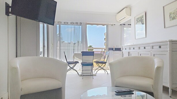Een moderne woonkamer met twee witte banken, een glazen salontafel en een eethoek met stoelen en een tafel.