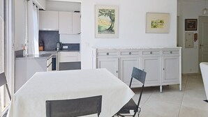 Een moderne keuken met witte kasten, een eettafel met stoelen en kunst aan de muren.