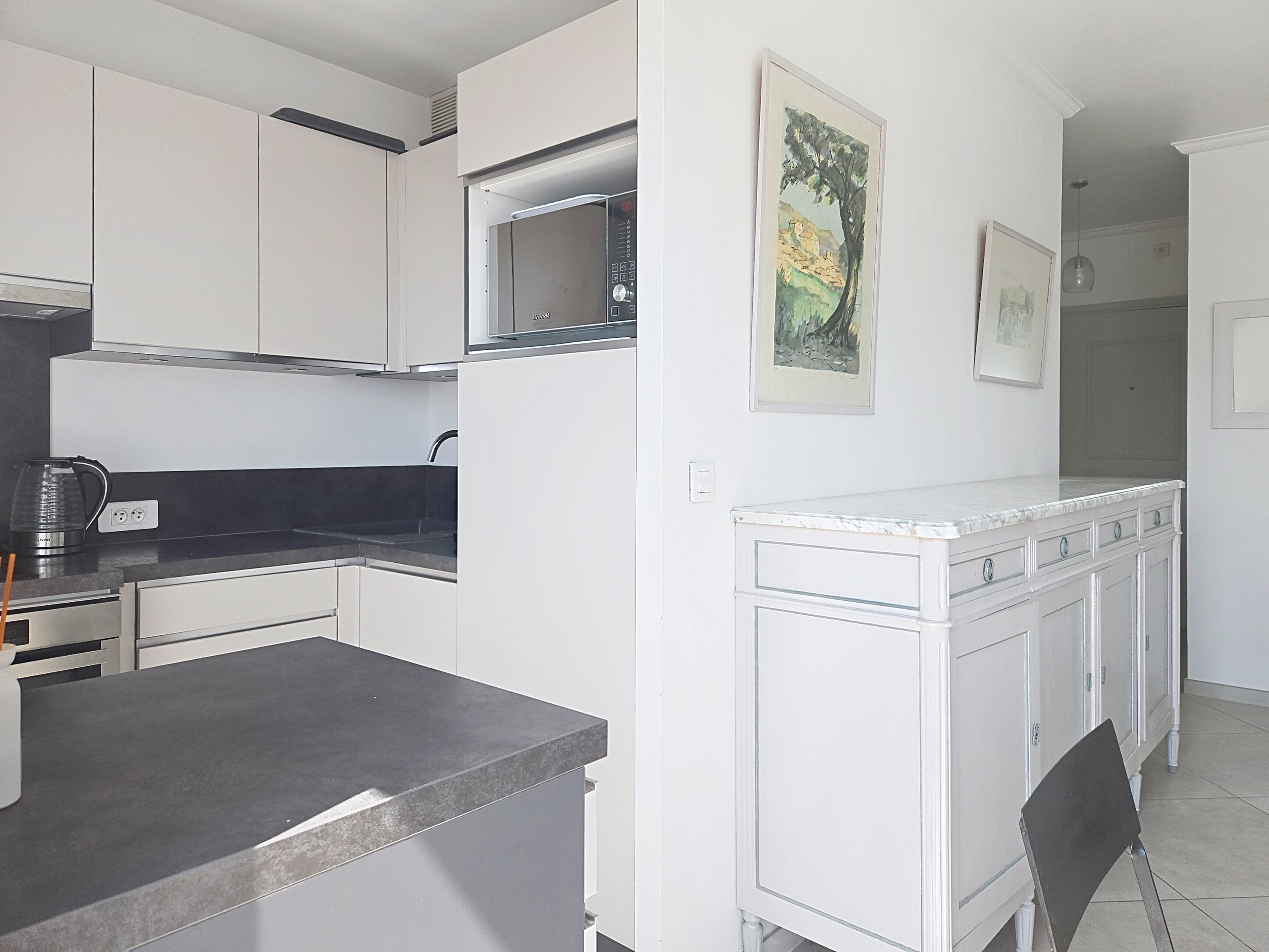 A modern kitchen with white cabinets, a black countertop, and a microwave.