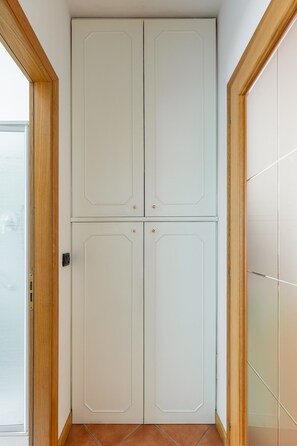Eine weiße Doppeltür mit Holzrahmen, ein Fliesenboden und eine Glastür links.
