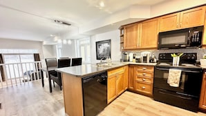 A modern kitchen with wooden cabinets, a black stove, and a microwave.