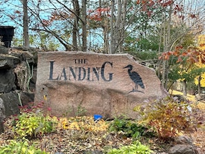 Kivitaulu, jossa lukee ”THE LANDING”, ja sen yhteydessä on kaiverrettu kuva linnusta. Taustalla on syksyistä lehtikariketta ja kiviä.